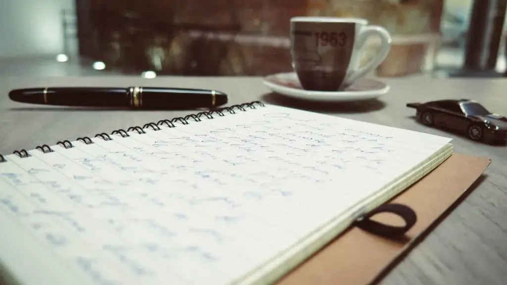 Notizbuch, Füller und Kaffeetasse auf dem Schreibtisch