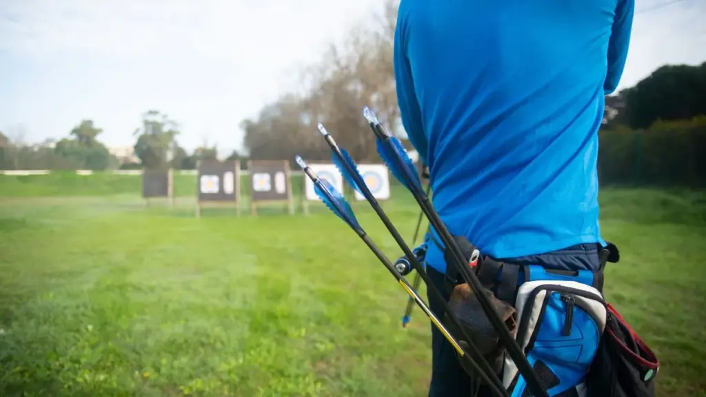 Pfeile mit Befiederung im Köcher einer Bogenschützin vor der Zielwiese